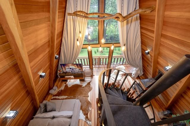 Interior do chalé com pé-direito alto e escada para o mezanino